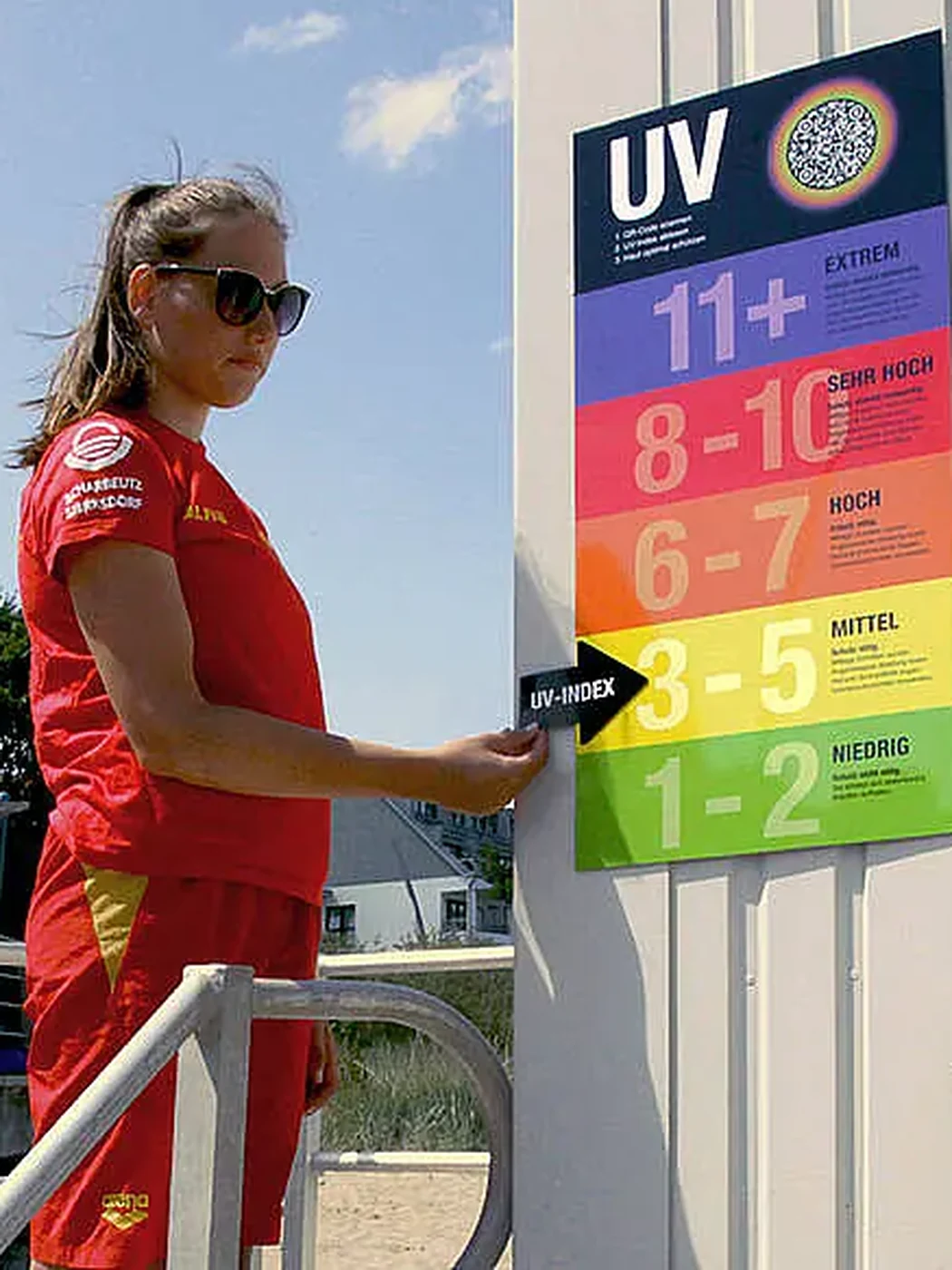 A lifeguard setting the current level on the UV Index board