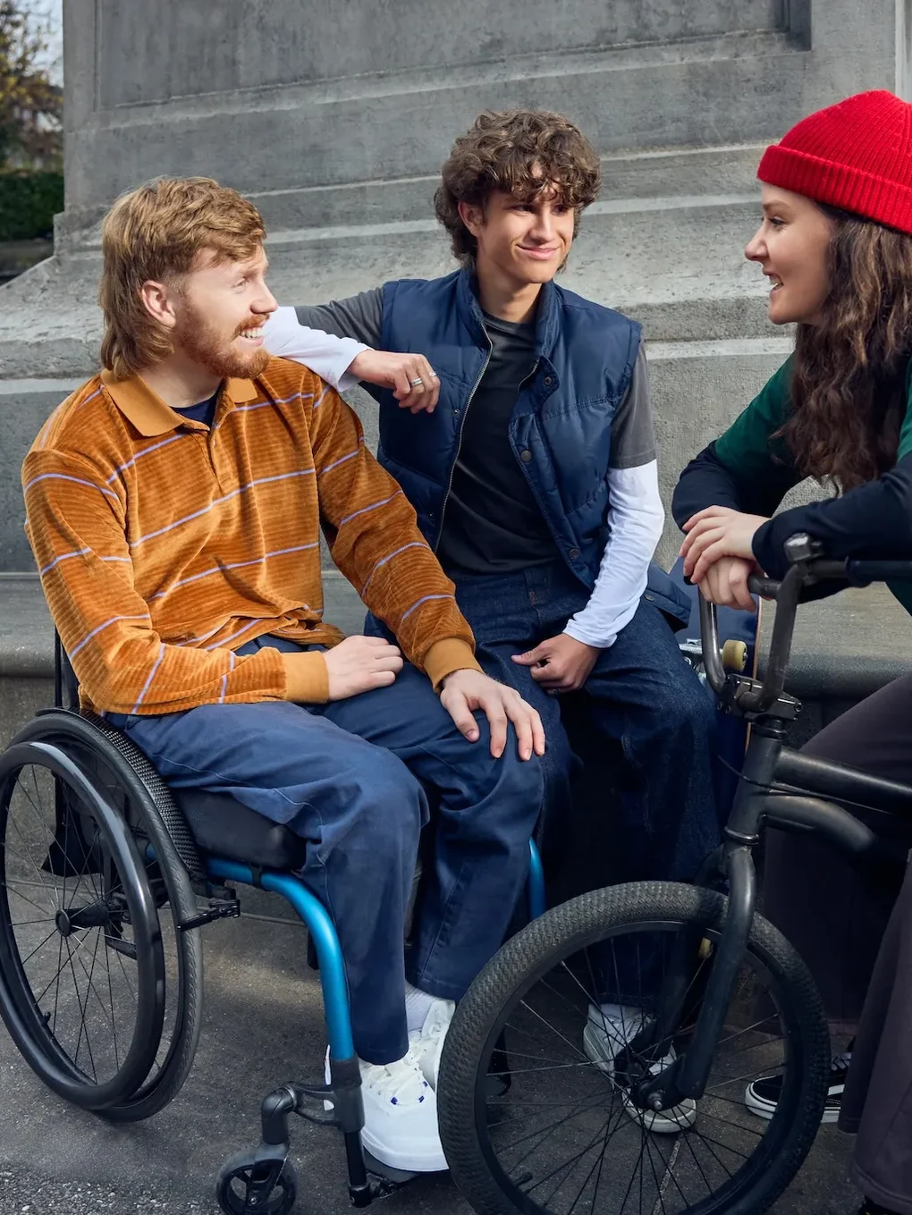 Campaign photography: a man in a wheelchair with two friends on a set of steps