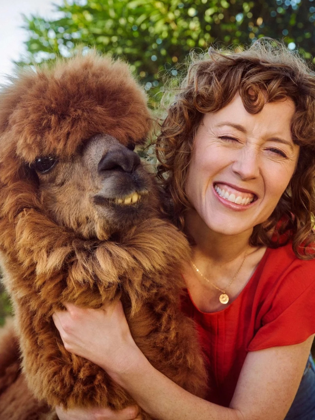 Campaign image: a woman laughing with an alpaca